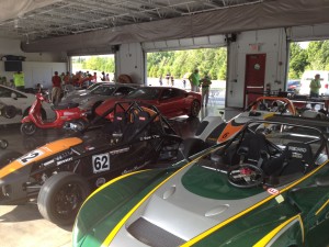 Green Lotus race car, Orange and black Ariel Atom, Indy car in the back, and a Ferrari 430 Scuderia in red